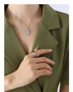 Close-up of butterfly pendant necklace and red gemstone ring worn with a green blazer