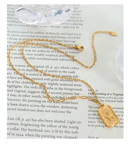 Detailed macro view of the butterfly embossed square pendant and gold plated link chain
