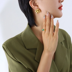 Exaggerated golden camellia earrings and green gemstone ring set worn by model