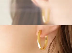 Détail de créoles dorées avec profil carré géométrique et finition polie brillante