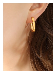 Gros plan de boucles d'oreilles minimalistes en titane doré en forme de U