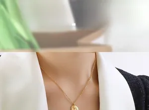 Close-up of golden O-chain necklace with a vintage oval embossed pendant on a model