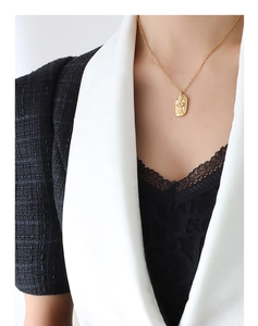 Detailed view of an oval gold pendant necklace featuring an artistic female body outline