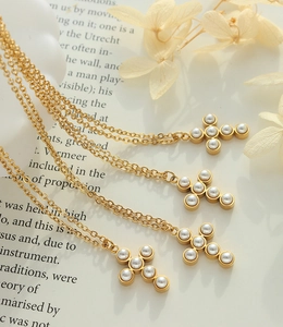 Vue détaillée de pendentifs croix dorés avec perles blanches sur un fond vintage rustique