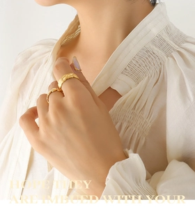 Close-up of gold interlocking rings featuring woven texture and wave design on finger