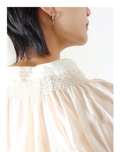 Close-up of interlocked gold and silver earrings worn by a model in profile