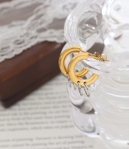 Detail shot of two-tone interlocking C-shaped hoop earrings on glass for jewelry display