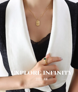 Detail showing vintage golden oval embossed pendant necklace with emerald green gemstone ring