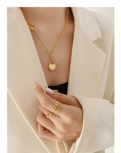 Détail du collier chaîne doré avec pendentif cœur et bagues superposées sur modèle
