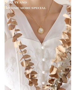 Pendentif ovale doré avec nacre sur dentelle blanche et feuilles d'eucalyptus séchées