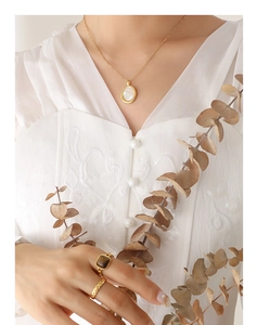 Détail du collier pendentif en nacre dorée et bagues sur mannequin avec dentelle