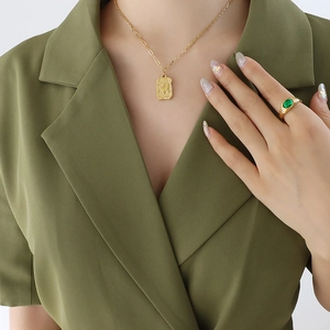 Retro gold butterfly pendant necklace and chunky green gemstone ring set on a model