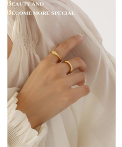 Detail of stacked gold-plated wavy rings with a minimalist geometric irregular design