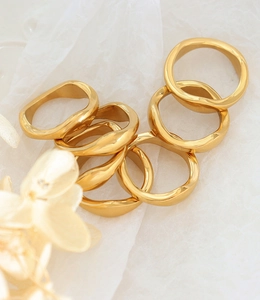 Macro view of wave-shaped 18k gold-plated stainless steel rings on white texture
