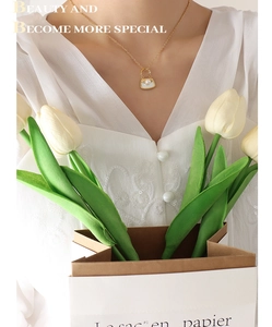 Détail du collier pendentif sac à main doré avec incrustation blanche et perle sur modèle