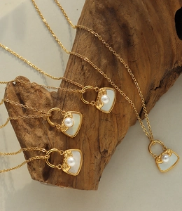 Détail macro de pendentifs sacs dorés avec nacre blanche et perles sur chaînes en O