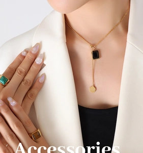 Détail d'un collier pendentif doré et de bagues avec pierres sur un blazer blanc