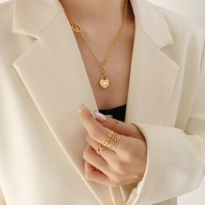 Collier doré avec pendentif cœur et bague texturée portés par un mannequin