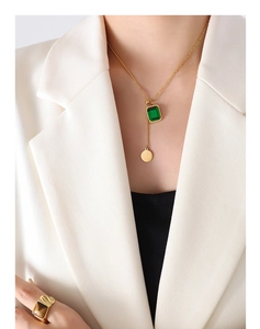 Collier doré avec pendentif vert et bague œil de tigre sur mannequin en costume blanc