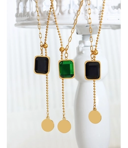 Détail de pendentifs en cristal carré sur des colliers dorés ajustables avec pompons