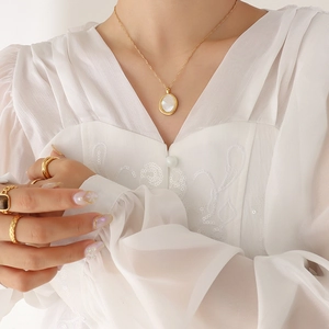 Collier en acier titane doré avec pendentif ovale en nacre et bagues dorées assorties