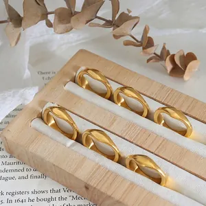Irregular wave gold rings in 18K plated finish arranged on a wooden jewelry display tray