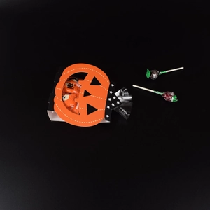 Halloween ghost pumpkin gift bag with orange paper handle and candies on black background