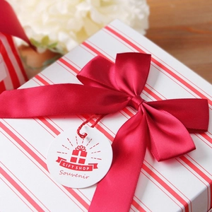 Rote gestreifte Geschenkbox mit großer burgunderroter Satinschleife und Geschenkanhänger