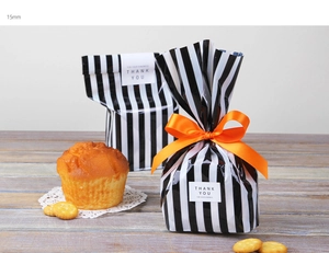 Details von schwarz-weiß gestreiften Geschenktüten mit orangefarbenem Band und Stickern