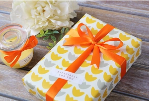 Details von leuchtend orangefarbenem Polyesterband und Geschenkpapier mit Blumenmuster