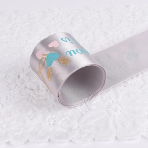 Silver satin ribbon roll with printed Love is text and heart motifs for gift wrapping