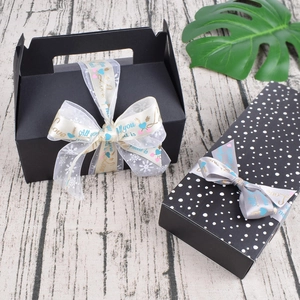 Elegant black gift boxes with decorative ribbons featuring All You Need Is Love text
