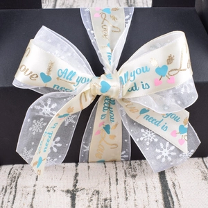 Close-up of decorative cream satin ribbon with love message and white mesh on black gift box
