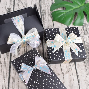 Detail of decorative satin ribbons with gold lettering on elegant gift box packaging