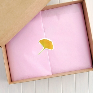 Détail macro d'autocollants feuilles de ginkgo jaunes sur papier de soie rose cadeau