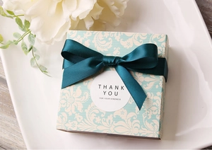 Dettaglio confezione regalo verde menta con motivi floreali e fiocco in nastro di raso verde