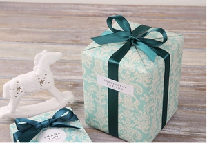 Dettaglio di una lussuosa scatola regalo azzurra damascata con fiocco di raso verde scuro