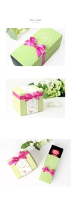 Detail view of green gift boxes with rose red ribbons and interior macaron display