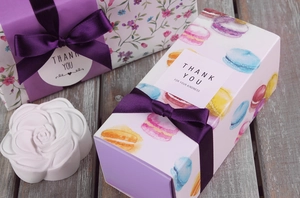 Detail von tiefviolettem Satinband als Schleife auf Geschenkboxen mit Blumenmuster