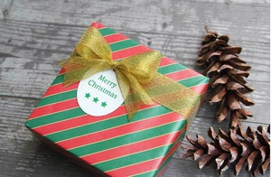 Detalle de caja de regalo navideña con rayas y un lazo de cinta brillante color dorado