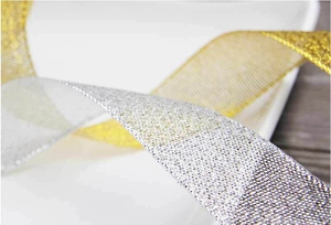 Detalle macro de cintas de malla metálica en oro y plata para envoltorios de regalo