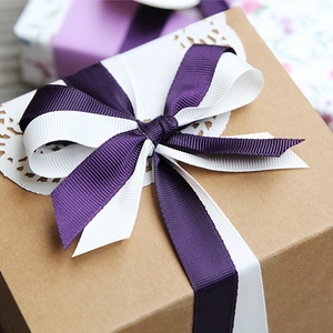 Purple and white grosgrain ribbon tied in a bow on a gift box, polyester packing tape