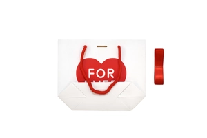Close-up of white gift bag with red heart pattern and Forever text plus a ribbon