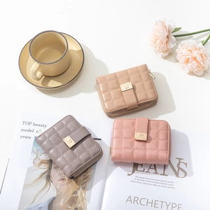 Tre portafogli in pelle PU trapuntata in beige, viola e rosa su una scrivania