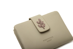 Close-up of greyish-green wallet with leaf buckle and fine lychee grain texture