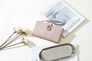 Detail view of pink PU leather wallet with leaf metal clasp and wristlet on art magazine