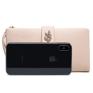 Detail of pink faux leather wallet with leaf charm next to a smartphone for size reference