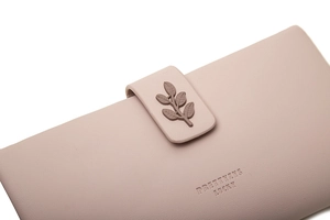 Detail of pink long wallet showing matte leather texture and 3D leaf charm decoration
