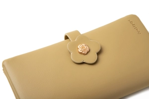 Detail of flower-shaped strap with gold rose hardware on a khaki long leather wallet