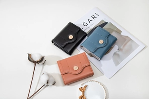 Detailed close-up of compact zip wallets in black, blue and orange with gold snap buttons